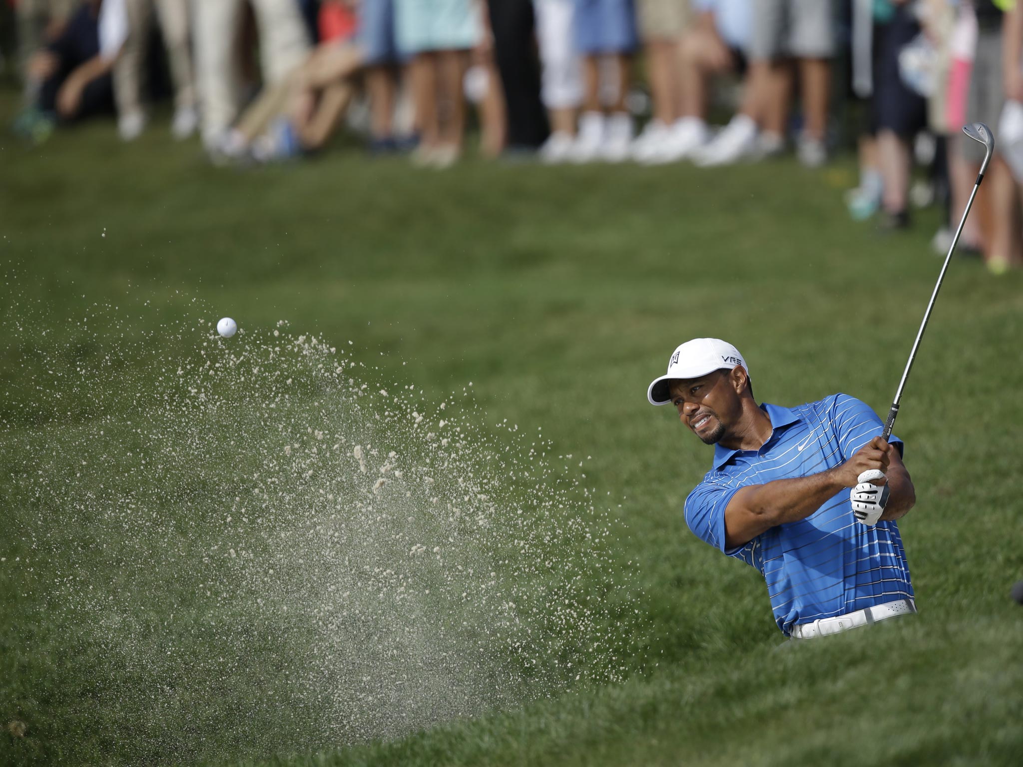 Tiger Woods chips out of a bunker on his way to a consolation birdie on the 18th hole yesterday