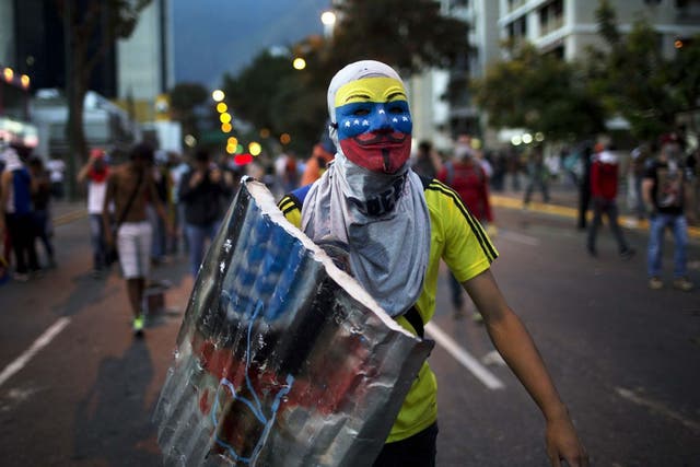 An anti-government demonstrator walks towards riot policemen during a protest in Caracas last night