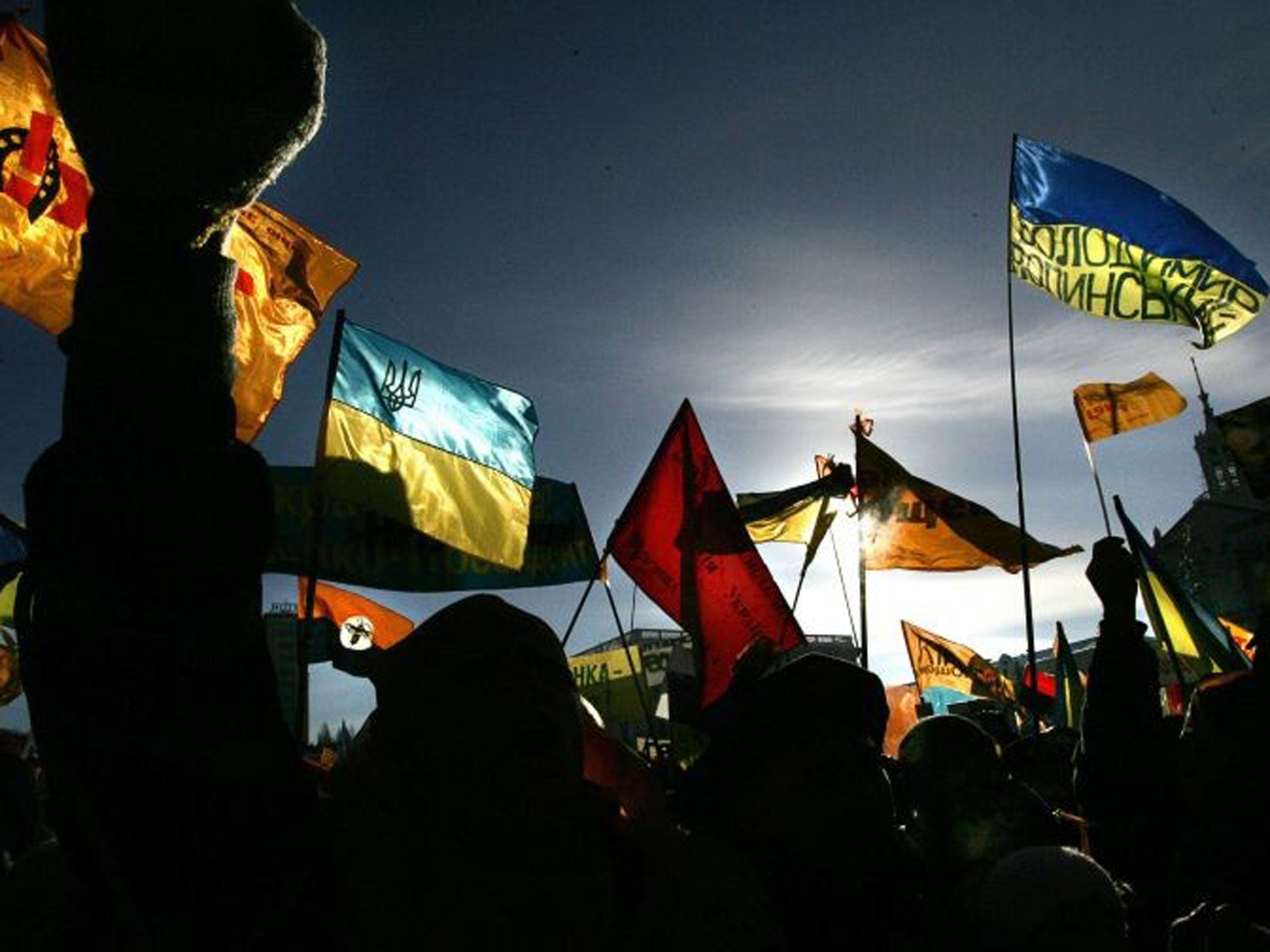 Silhouetted supporters of the pro-Western opposition leader Viktor Yushchenko wave flags during a rally in central Kiev
