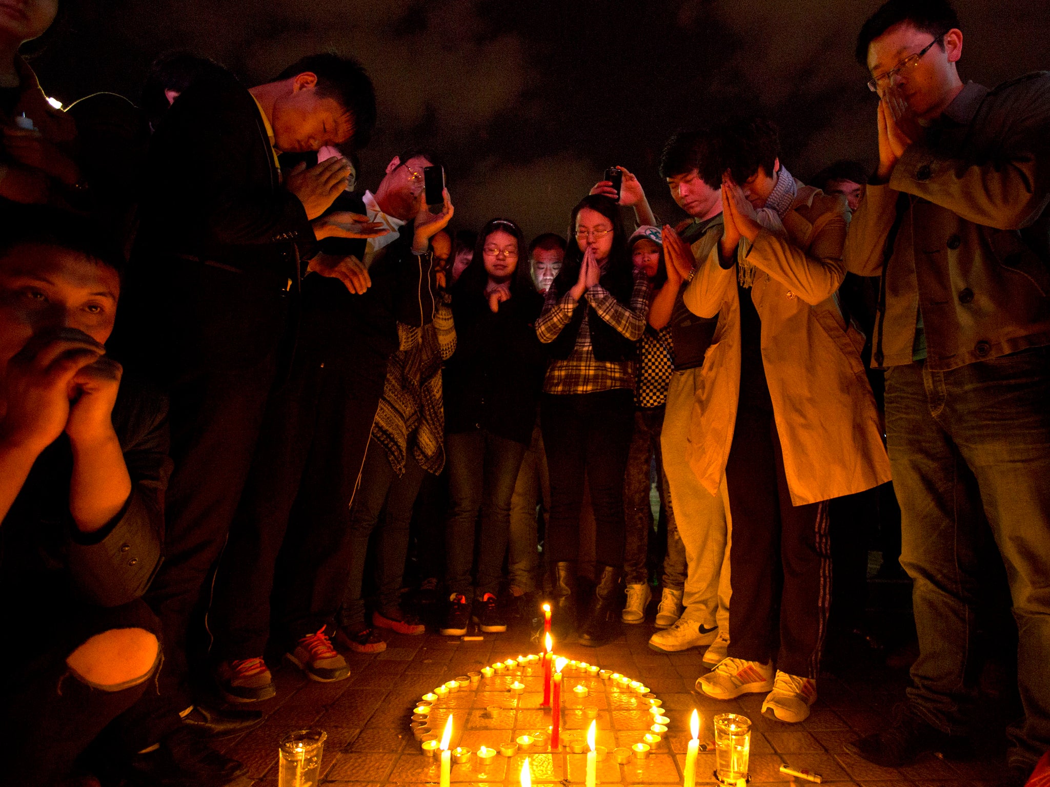 People light candles and pray for the victims on a square outside the Kunming Railway Station following the attack