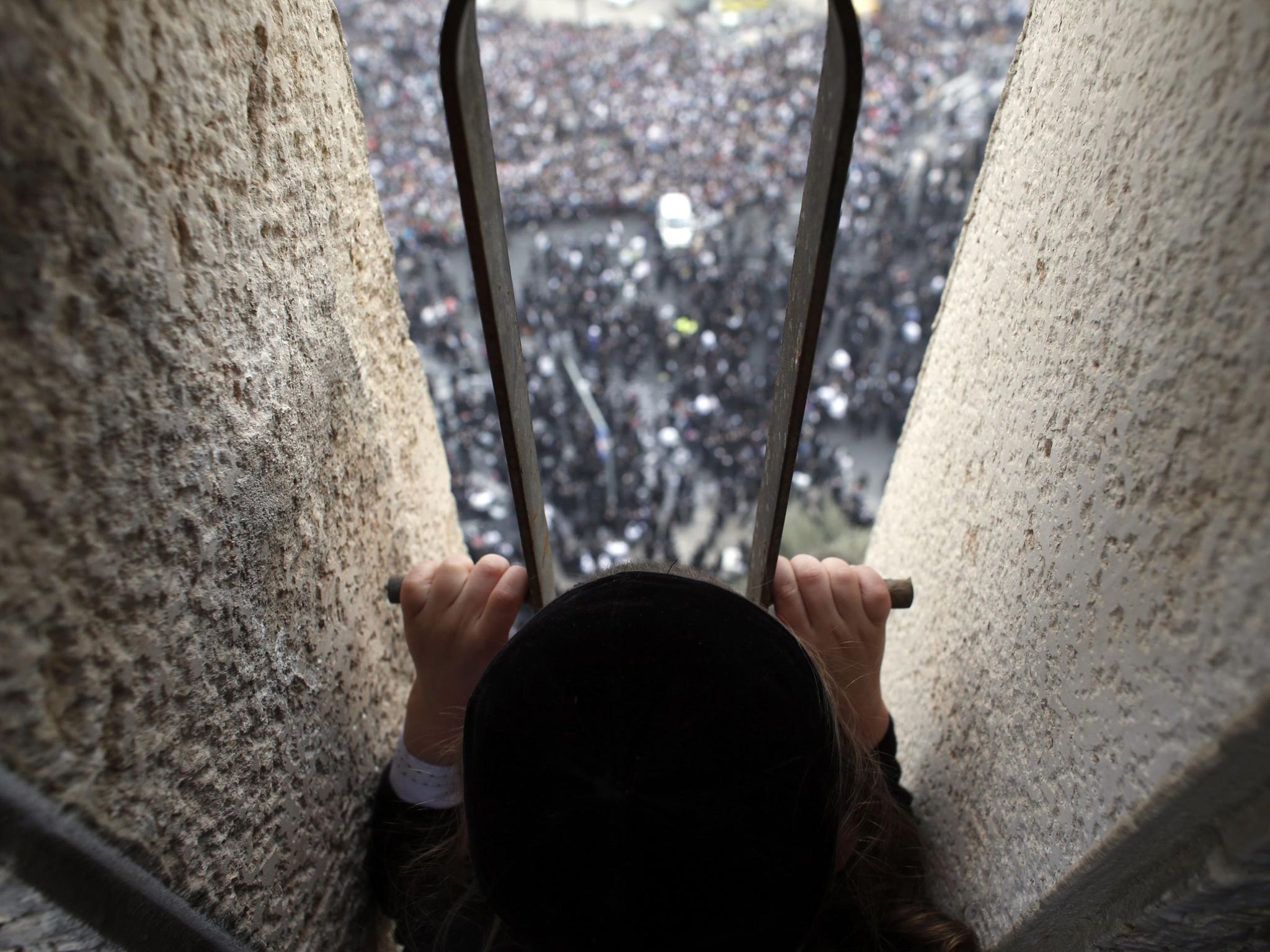 An ultra-Orthodox Jewish boy looks down from a balcony at a mass prayer in Jerusalem. Hundreds of thousands of ultra-Orthodox Jews held a mass prayer in Jerusalem on Sunday