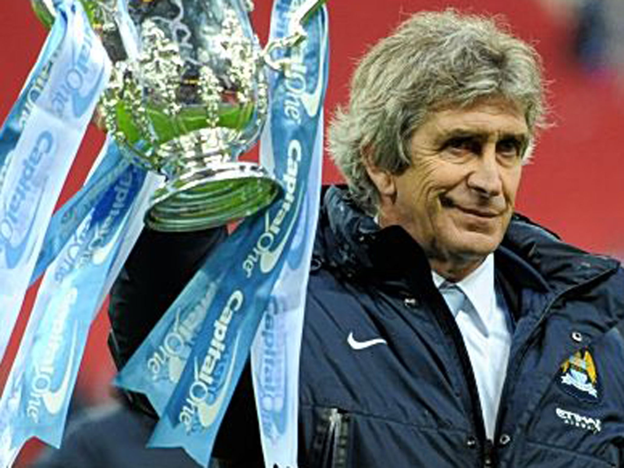 Manuel Pellegrini holds up the first major trophy he has won in Europe