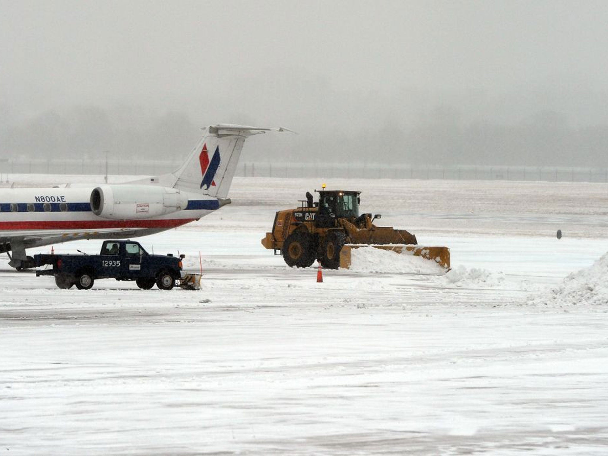 Workers use snowplows to clean a tarmac at the Reagan National Airport during a snow storm in Washington, DC