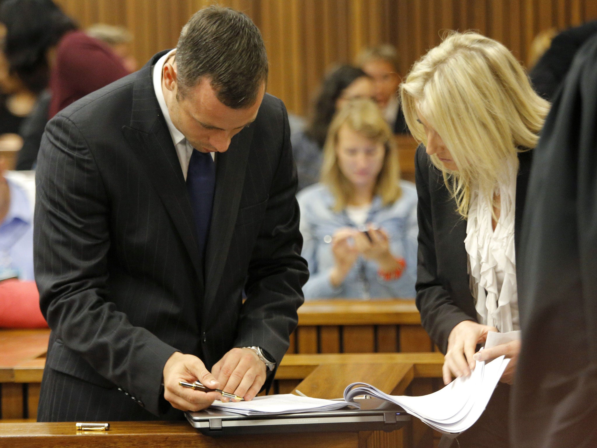 Oscar Pistorius looks at his defense team paperwork during a break on the second day of his trial at the North Gauteng High Court in Pretoria 