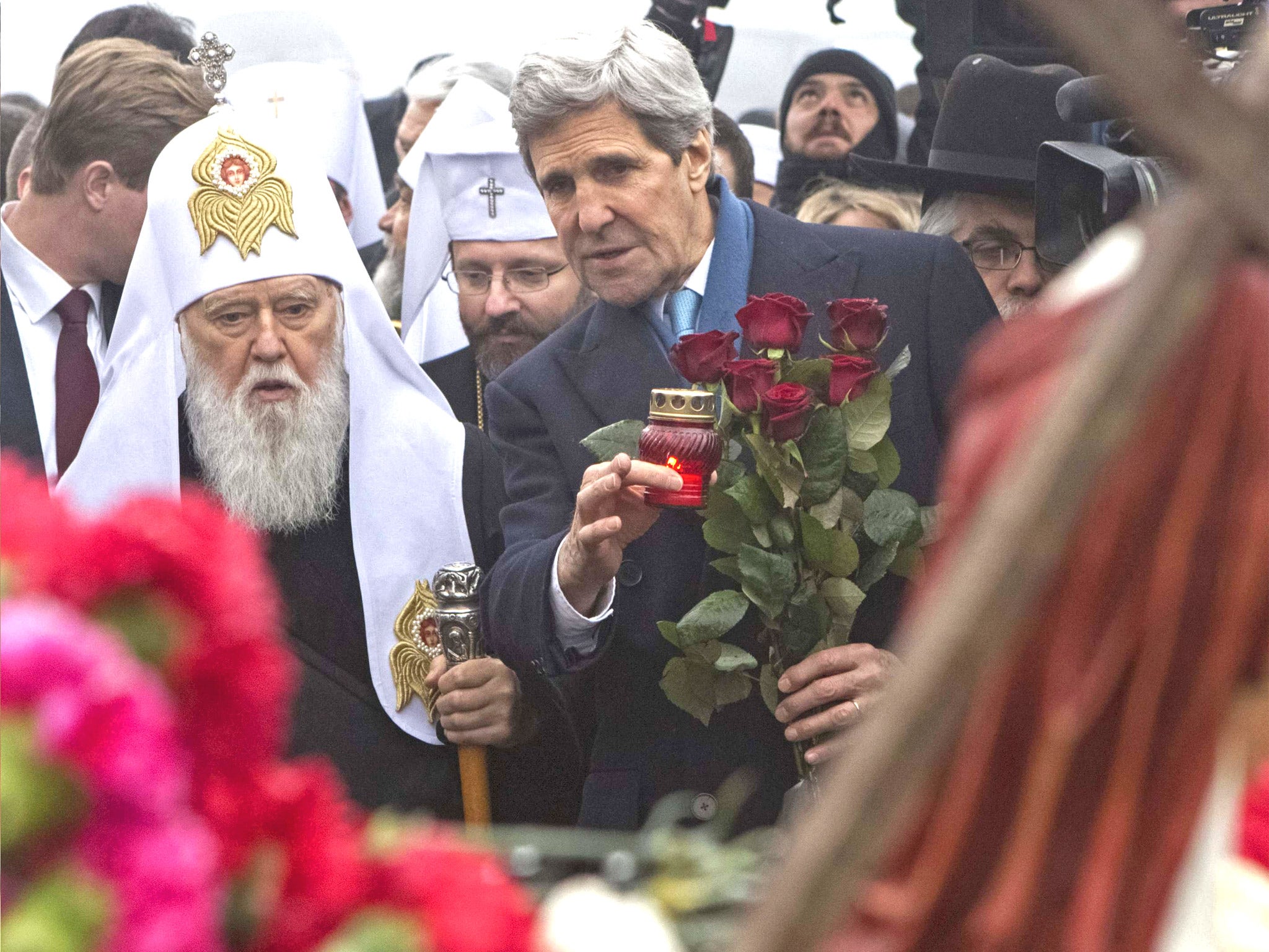 US Secretary of State John Kerry holds a candle as he lays roses atop the Shrine of the Fallen in Kiev