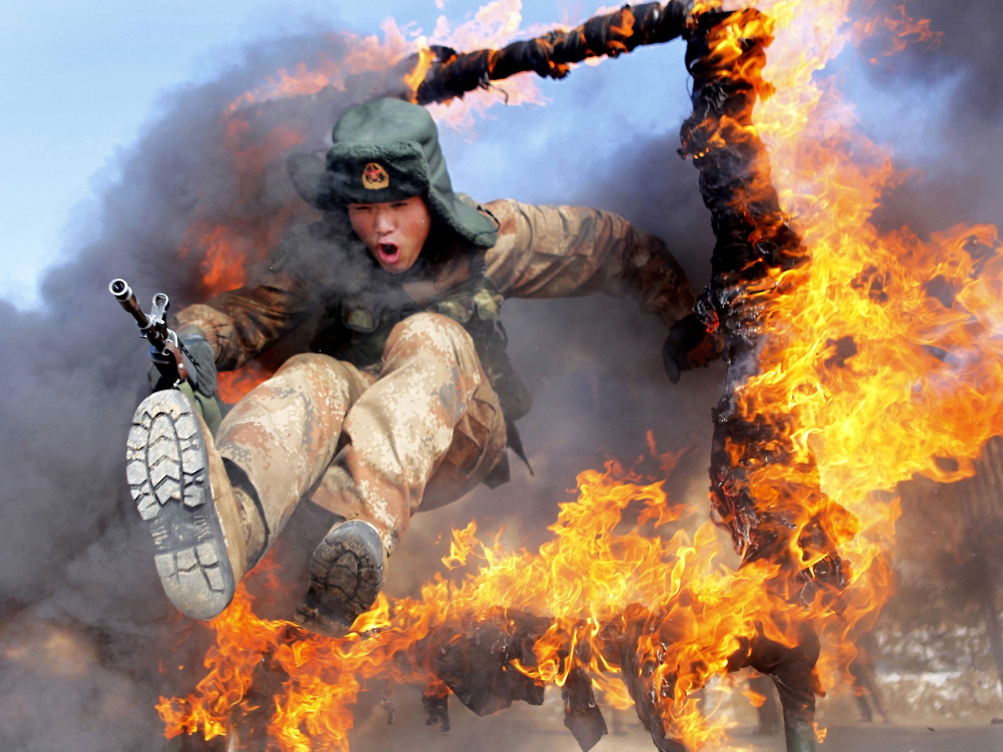 A frontier soldier from the People's Liberation Army jumps through a ring of fire as part of training in Heihe, Heilongjiang province