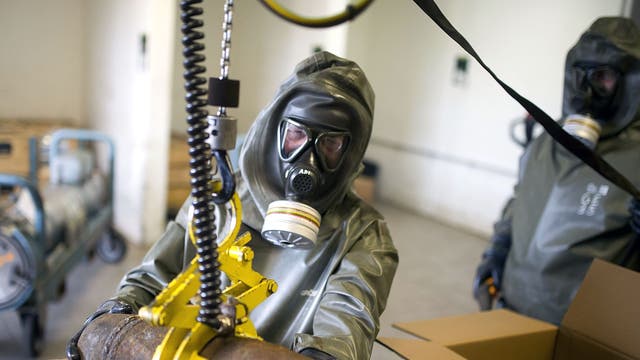Workers in protective clothing holds a dummy grenade