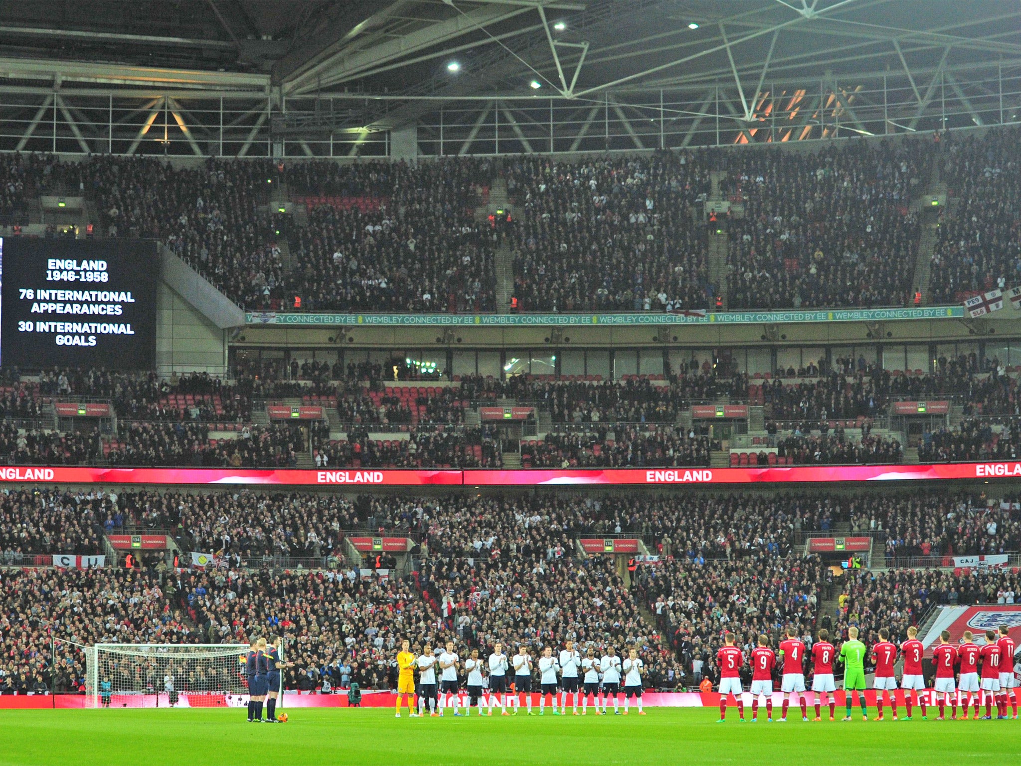 The players join the crowd in a minutes applause for the late former Denmark team coach Richard Moller Nielsen and the late England international footballer Tom Finney