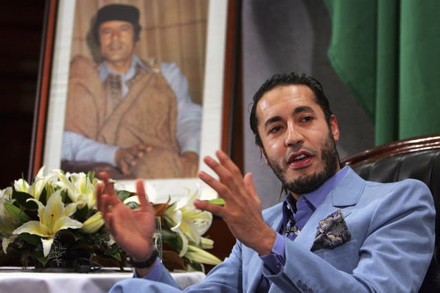 Al Saadi Gaddafi, the third son of Libyan leader Muammar Gaddafi (portrait on left), speaks at a news conference in Sydney in this February 7, 2005 file photo