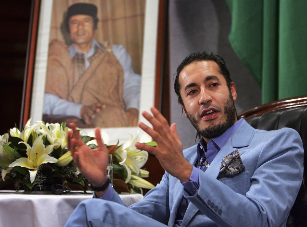 Al Saadi Gaddafi, the third son of Libyan leader Muammar Gaddafi (portrait on left), speaks at a news conference in Sydney in this February 7, 2005 file photo