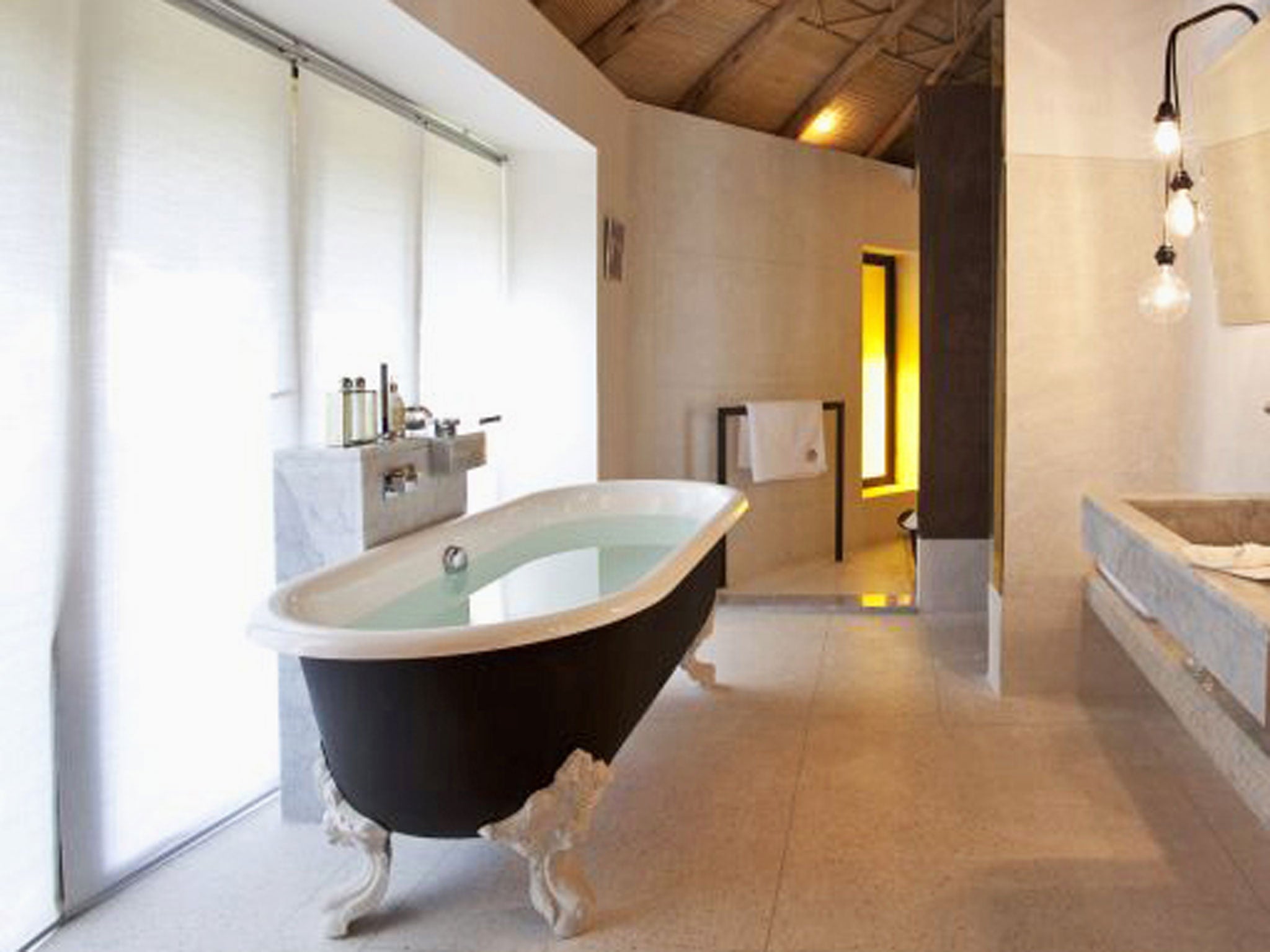 A tadelakt (waterproof lime plaster) wall separates the bathroom where there is a monsoon shower with a stone bench