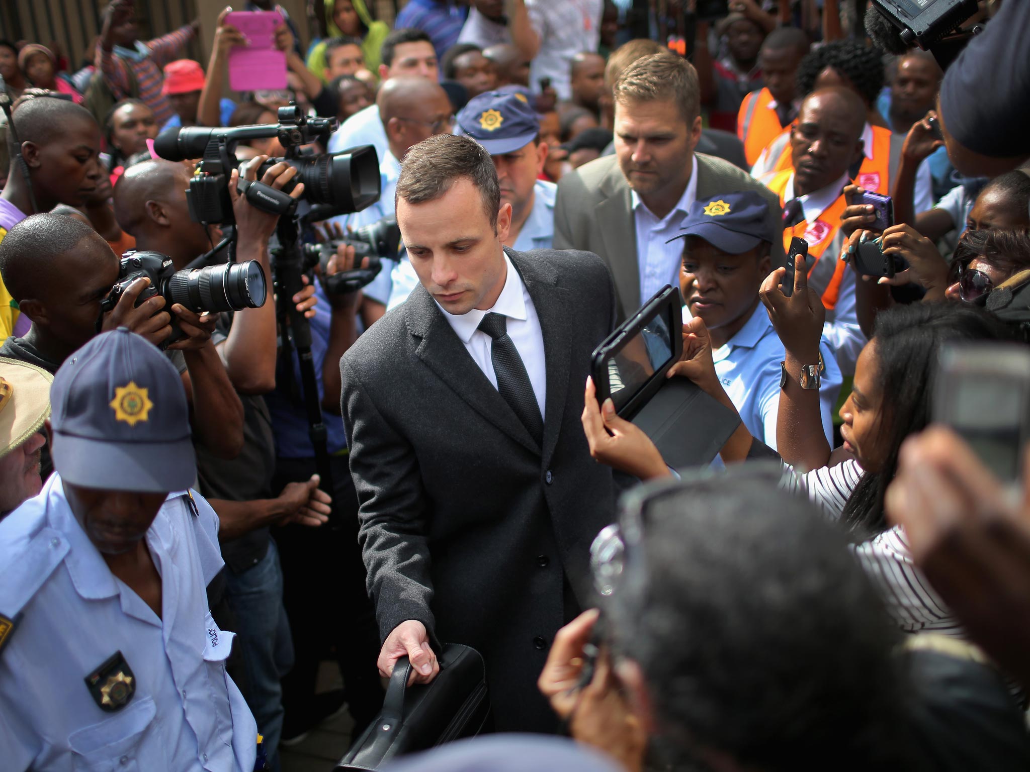 Oscar Pistorius is surrounded by police and media as he leaves North Gauteng High Court