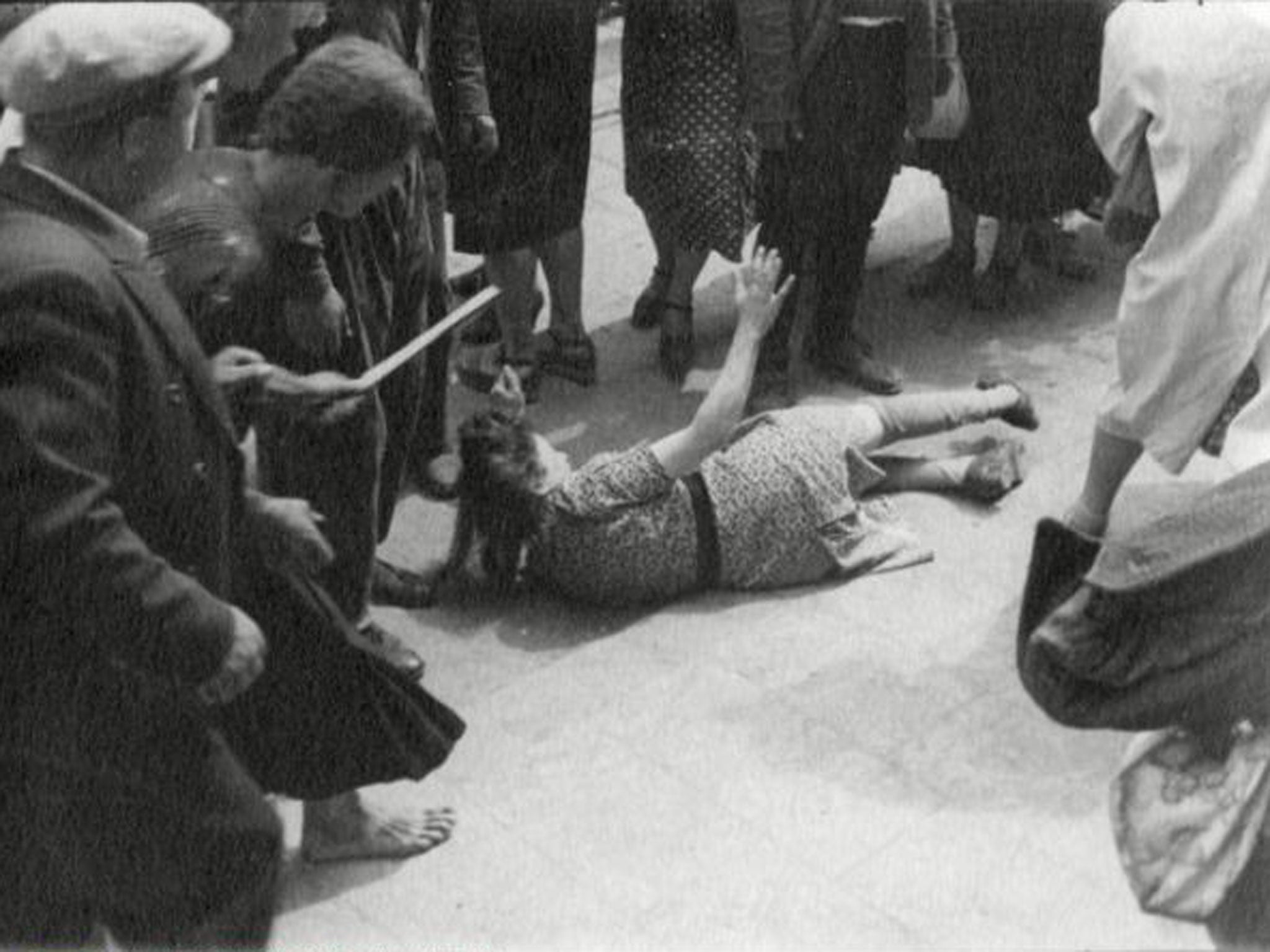 A crowd surrounds a young woman during the1941 progrom