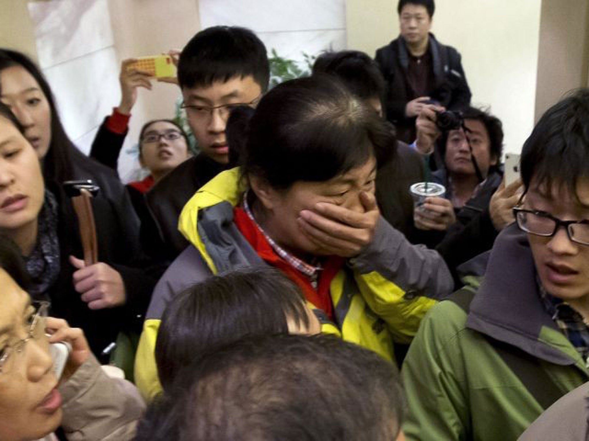 Relatives of people on board the plane are surrounded by press as the tragedy unfolds