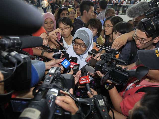 A family member of passengers aboard a missing Malaysia Airlines plane is mobbed by journalists at Kuala Lumpur International Airport