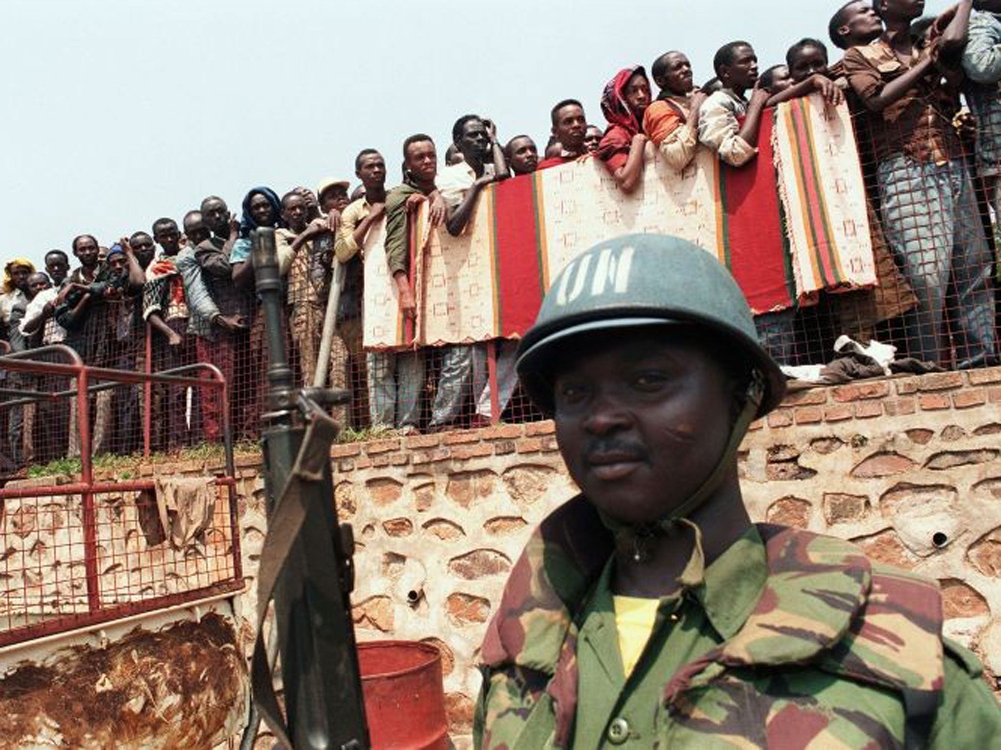 A Ghanaian UN soldier watches over Tutsi refugees being led from a Kigali church in June 1994