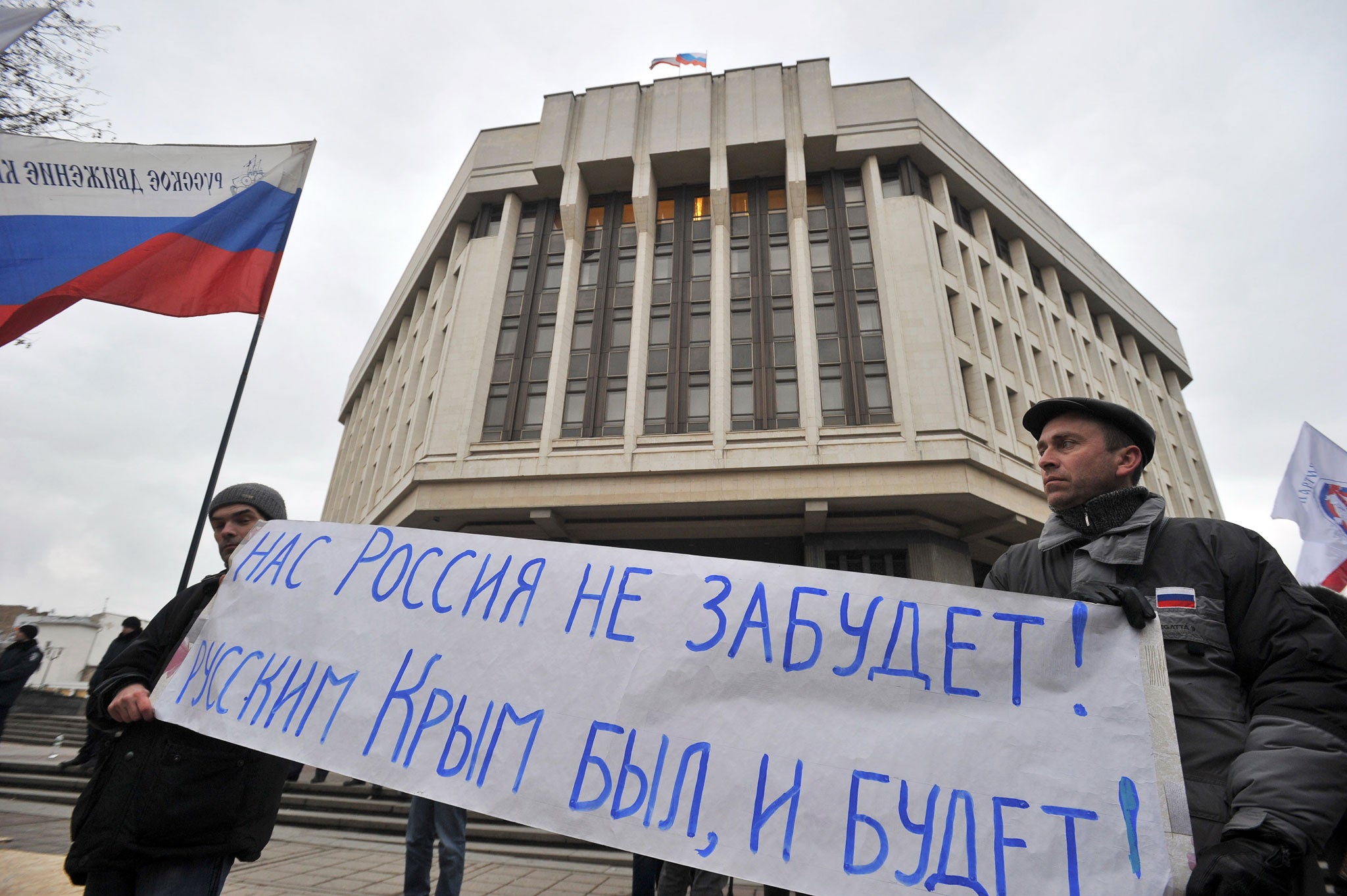 ro-Russia protesters hold a banner (R) reading 'Russia will not forget us ! Crimea was and will be Russian !' and the Russian flag (L) during a rally in front of the local parliament building