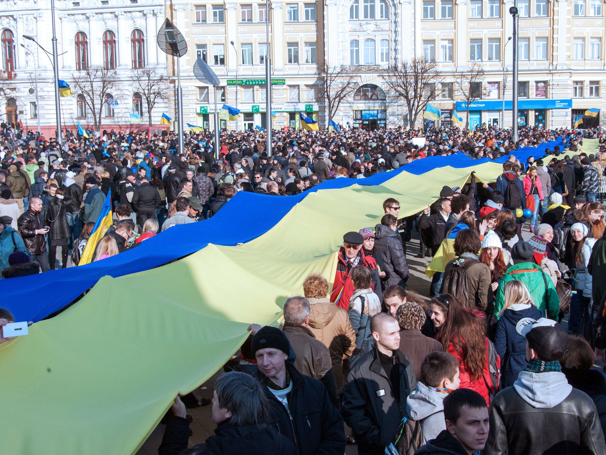 Protesters carry a giant Ukrainian flag during yesterday’s anti-war rally in Kharkiv, north-eastern Ukraine, as the world’s leaders seek a solution to the stand-off