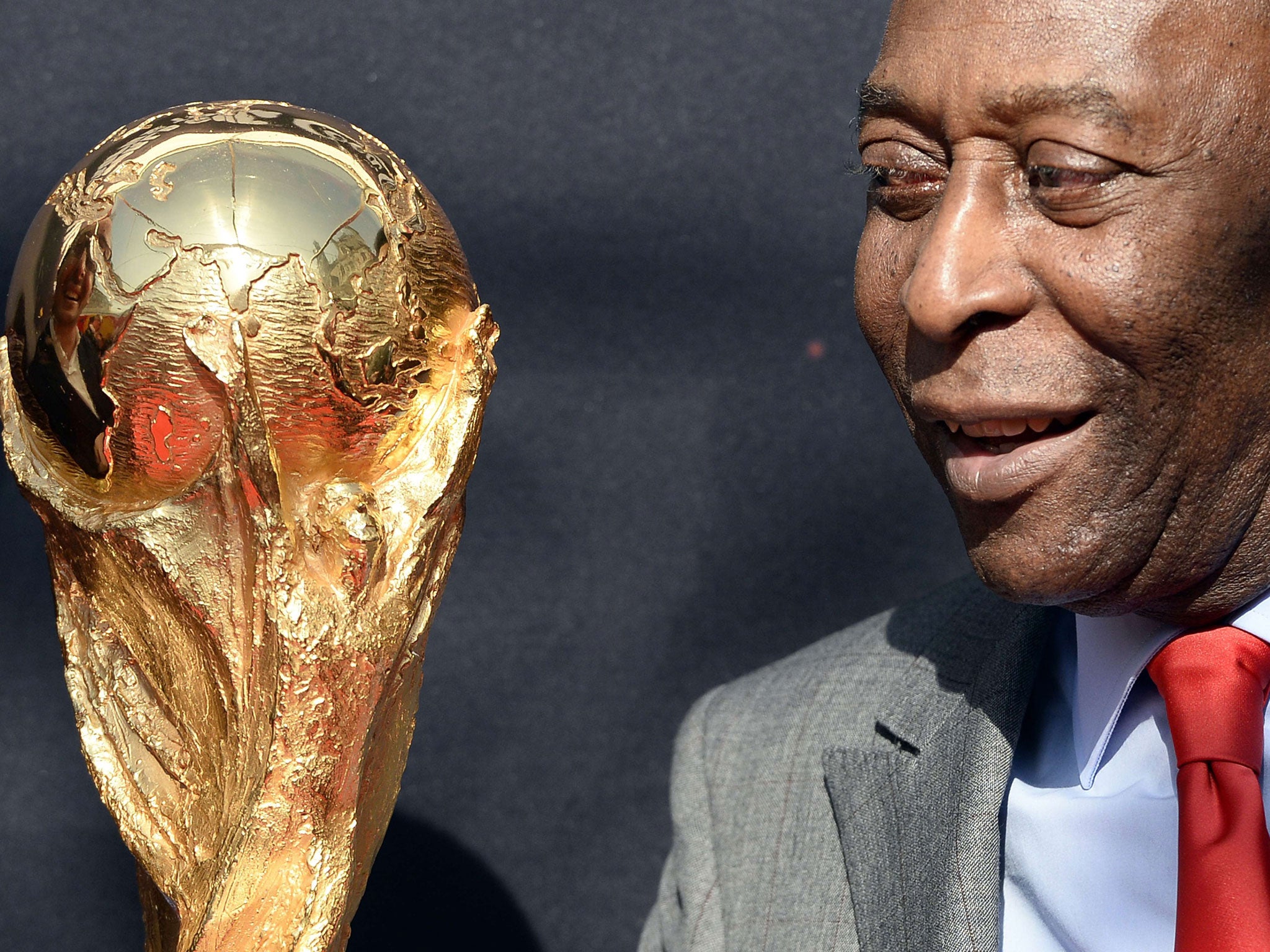 Brazilian football legend Pele looks at the FIFA World Cup trophy during a FIFA event outside the Hotel de Ville in Paris