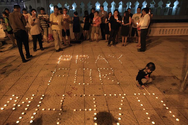 A girl lights a candle next to a message reading 'Pray for MH370' during a candlelight vigil for passengers of the Malaysia Airlines flight