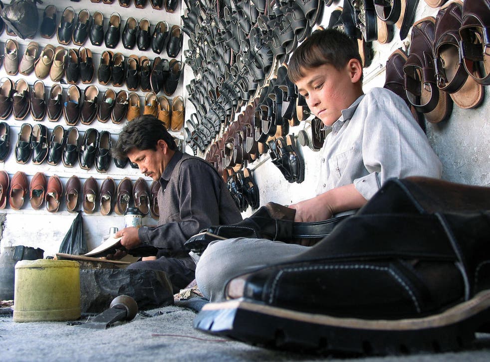 A Pakistani boy helps his father to make 'Chappal' or sandal at their workshop in Quetta - Paul Smith sell a £300 version in their London store
