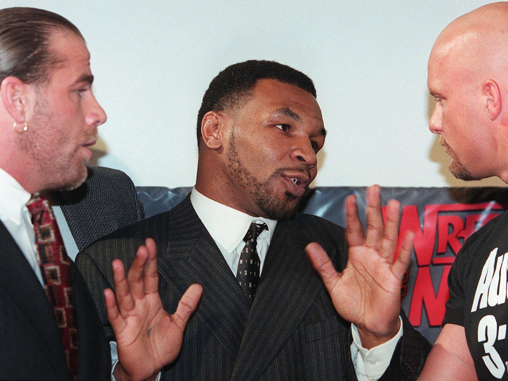 Former world heavyweight boxing champion Mike Tyson (C) acts as a referee between World Wrestling Federation wrestlers Shawn Michaels (L) and Steve Austin
