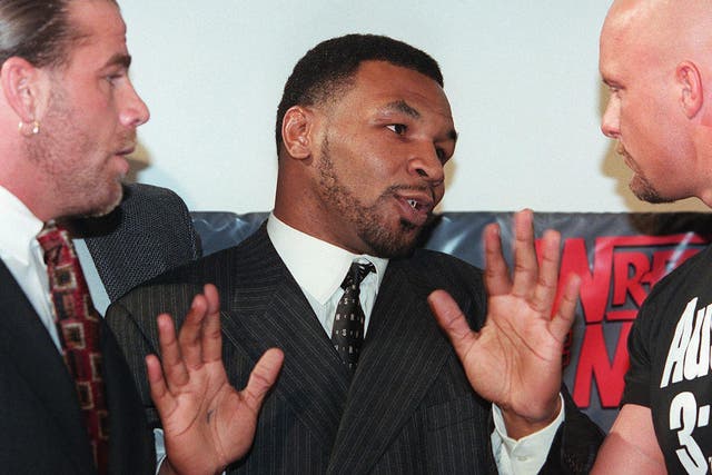 Former world heavyweight boxing champion Mike Tyson (C) acts as a referee between World Wrestling Federation wrestlers Shawn Michaels (L) and Steve Austin