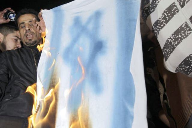 A copy of the Israeli flag is burned during a protest following the shooting of Palestinian-Jordanian judge Raed Alaa el-Deen Zaeiter
