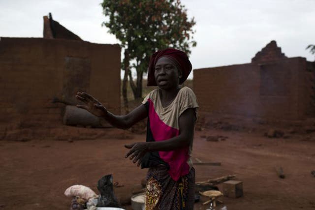 A woman gestures near her destroyed home after her village was almost completely destroyed during a Seleka attack