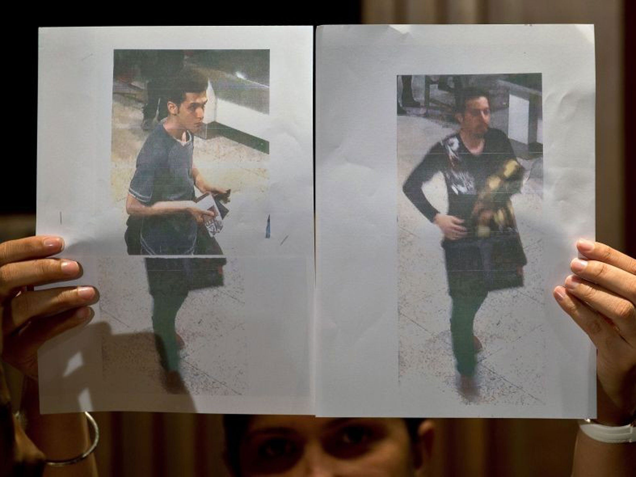 A Malaysian police official displays photographs of the two men who boarded the Malaysia Airlines MH370 flight using stolen European passports