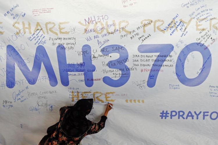 A woman writes a message of support and hope for passengers of the missing Malaysia Airlines MH370
