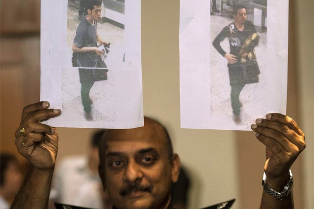 A Malaysian Police officer holds photos of two suspects believed to have travelled with stolen passports on the missing Malaysian Airlines flight