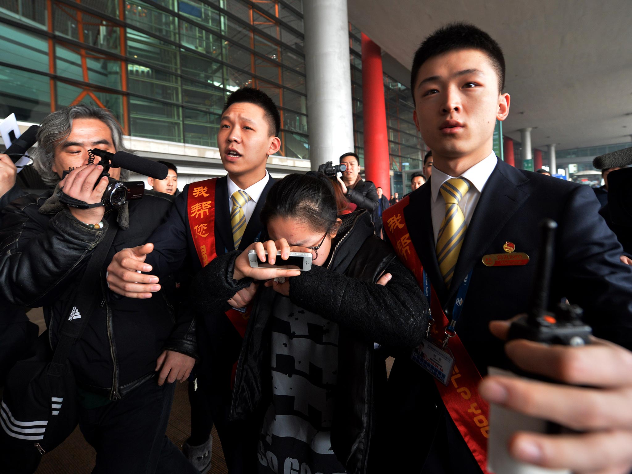 A crying woman is escorted to a bus for relatives at the Beijing Airport after news of the missing Malaysia Airlines Boeing 777-200 plane