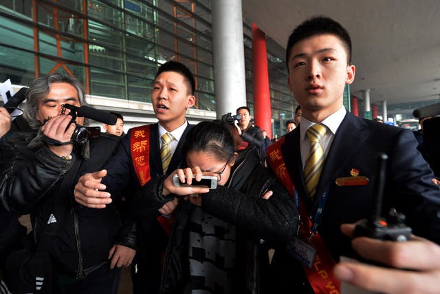 A crying woman is escorted to a bus for relatives at the Beijing Airport after news of the missing Malaysia Airlines Boeing 777-200 plane 