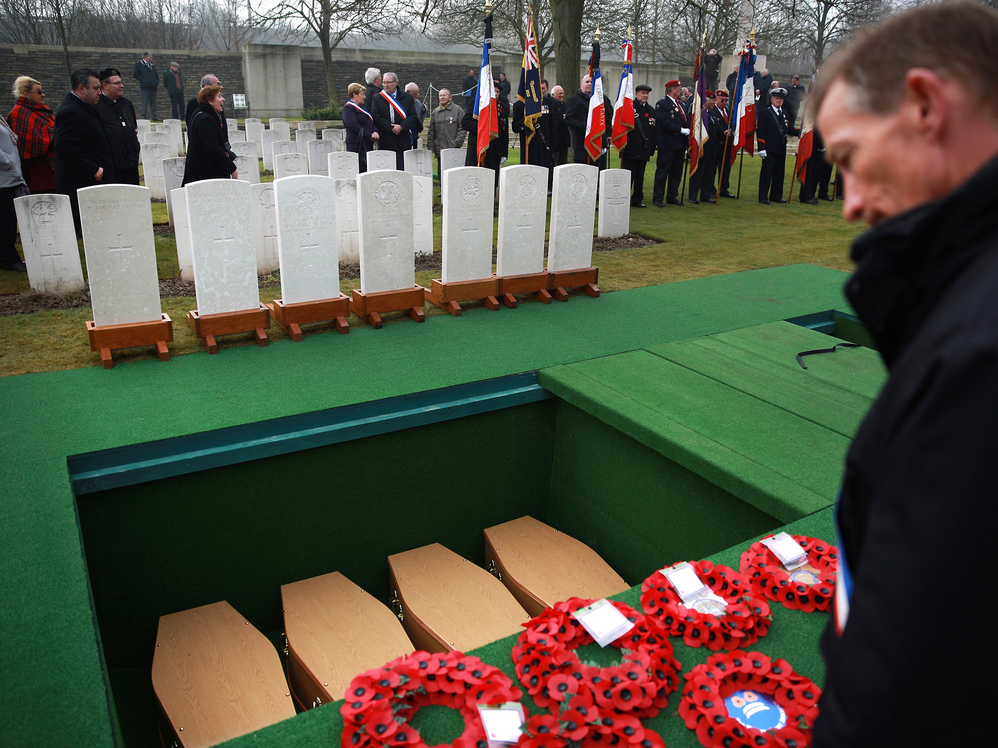 A mourner looks at coffins of British World War One soldiers after a re-burial ceremony at Loos British Cemetery on March 14, 2014 in Loos-en-Gohelle, France. Almost 100 years after they were killed in action in the World War One battle of Loos in 1915, twenty British soldiers have been re-interred in the Commonwealth War Graves Commission Loos British Cemetery in Northern France (Getty)