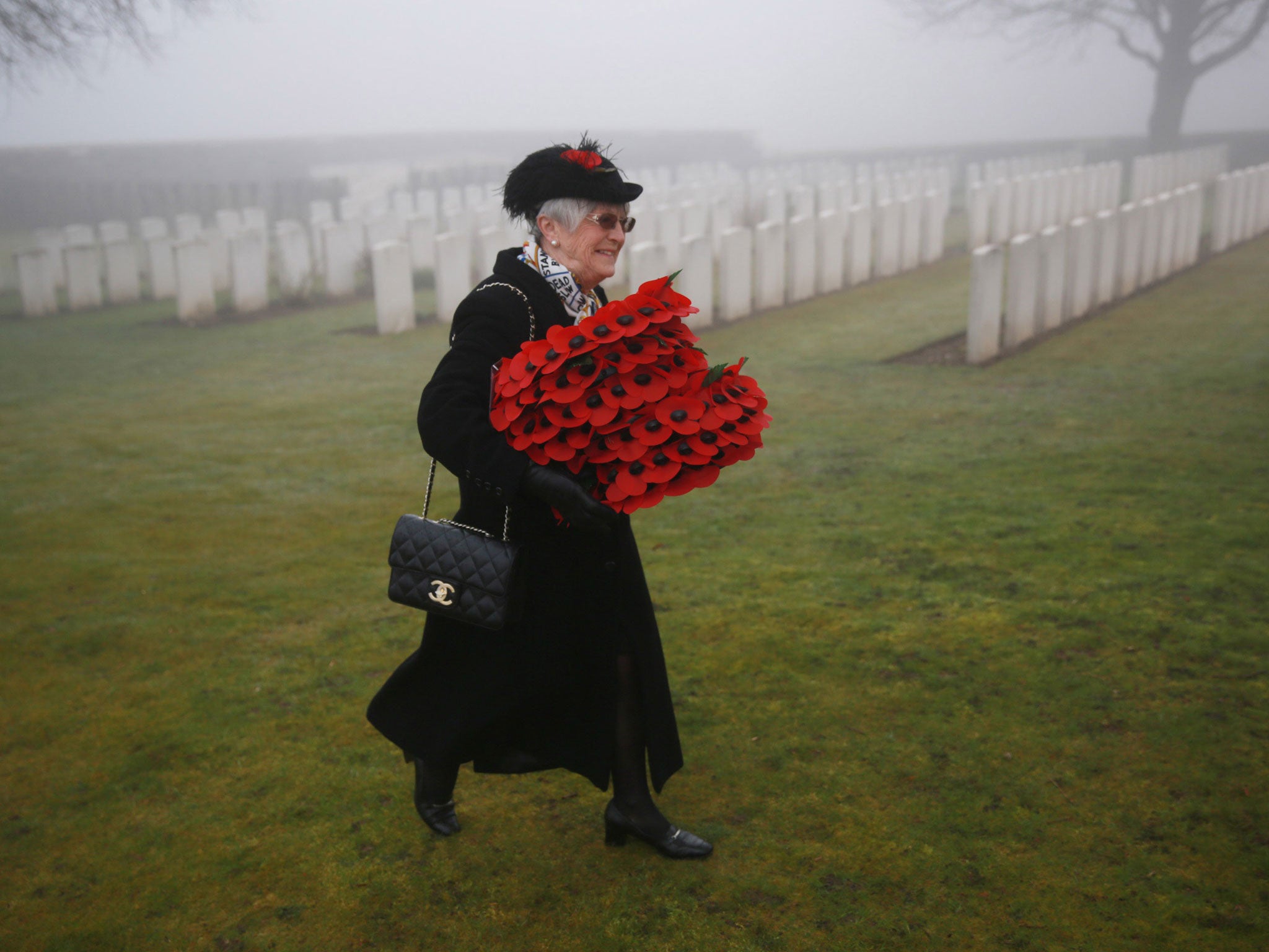A mourner carries wreaths before the re-burial of Private William McAleer at Loos British Cemetery in Loos-en-Gohelle