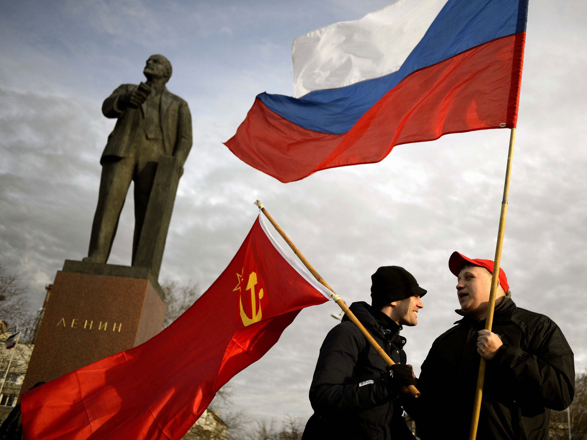 Pro-Russian protesters hold a Russian, Crimean and Soviet flags during their rally at Lenin Square in Simferopol, Ukraine