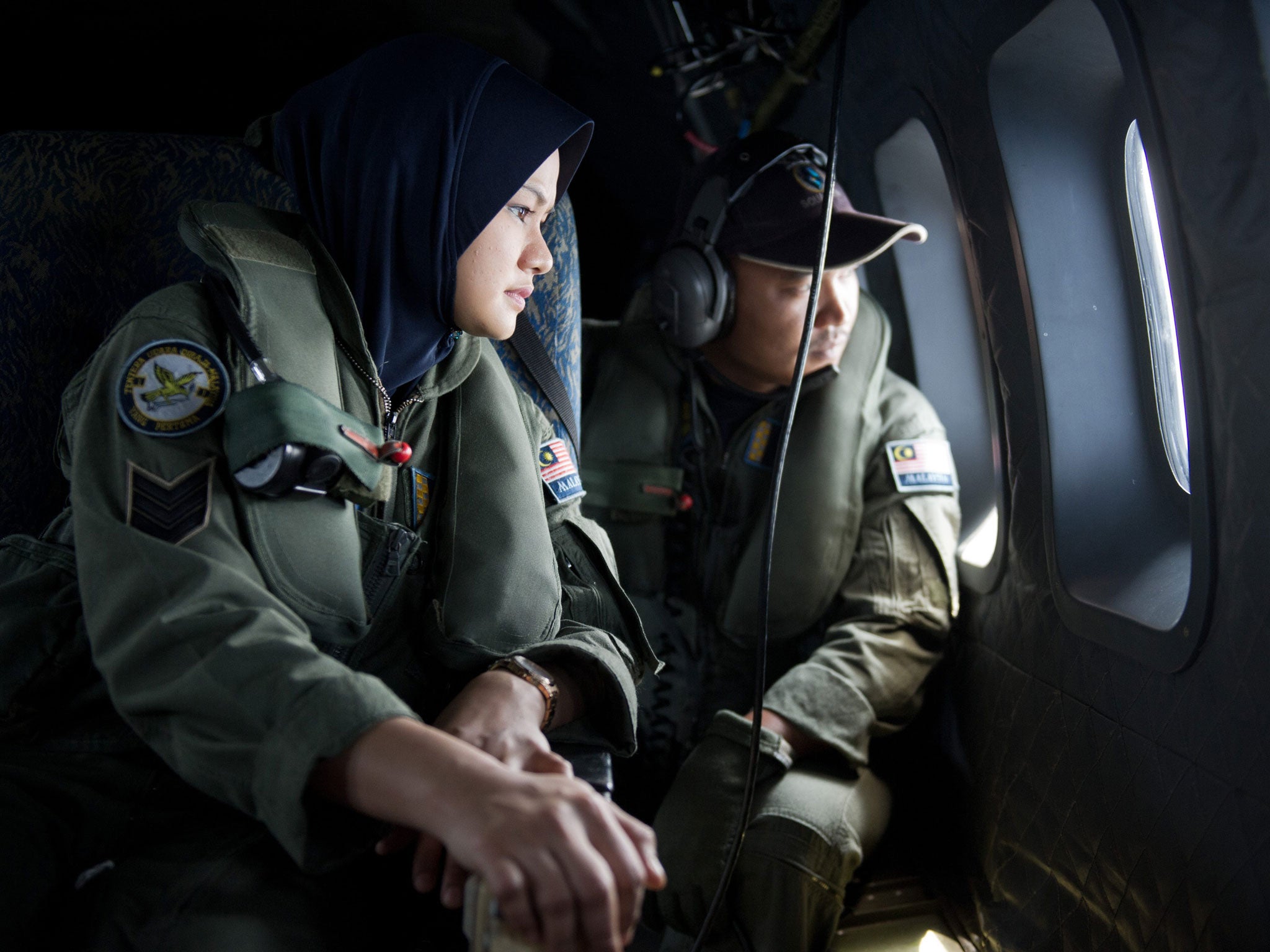 Crew members look outside windows from a Malaysian Air Force CN235 aircraft during a search and rescue (SAR) operation to find the missing Malaysia Airlines flight MH370 plane over the Strait of Malacca