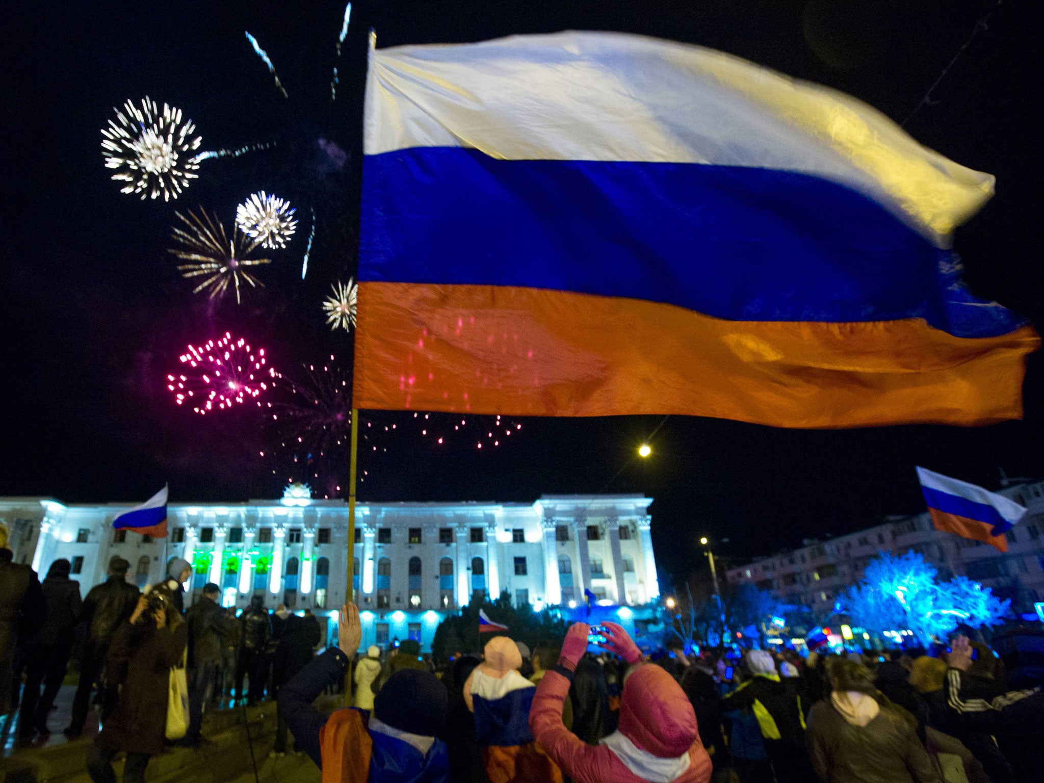 People watch fireworks and wave Russian flags during celebrations after the preliminary results of today's referendum are announced on Lenin Square in the Crimean capital of Simferopol