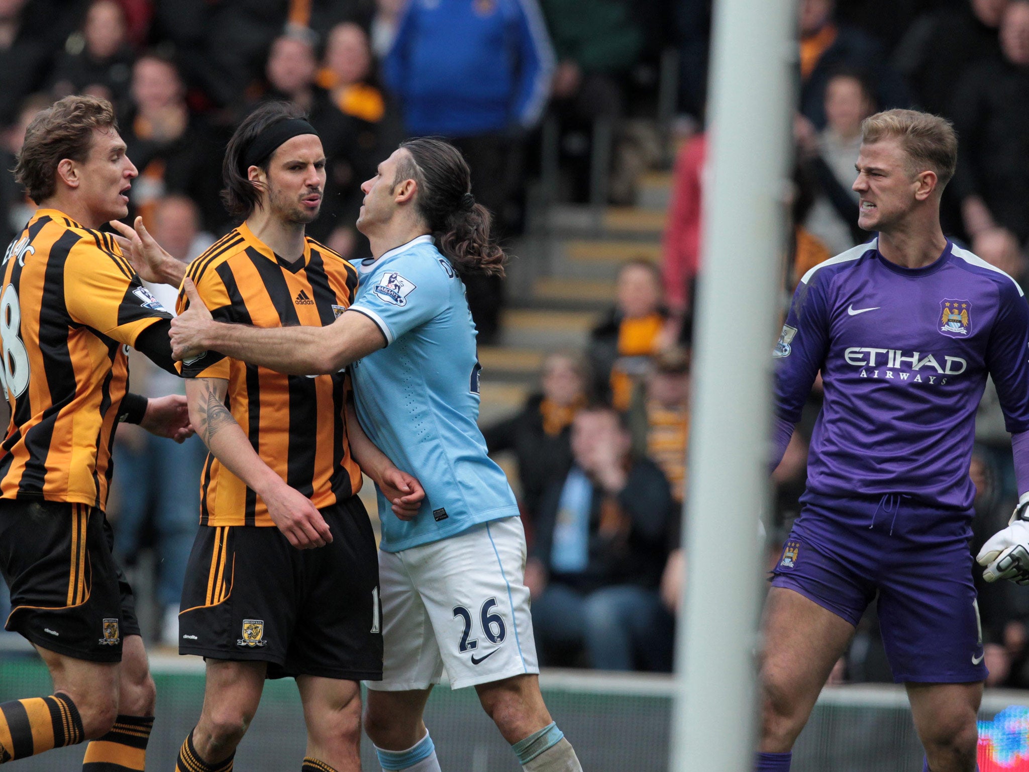 Hull City's George Boyd is held by Manchester City's Argentinian defender Martin Demichelis amid a confrontation with Joe Hart