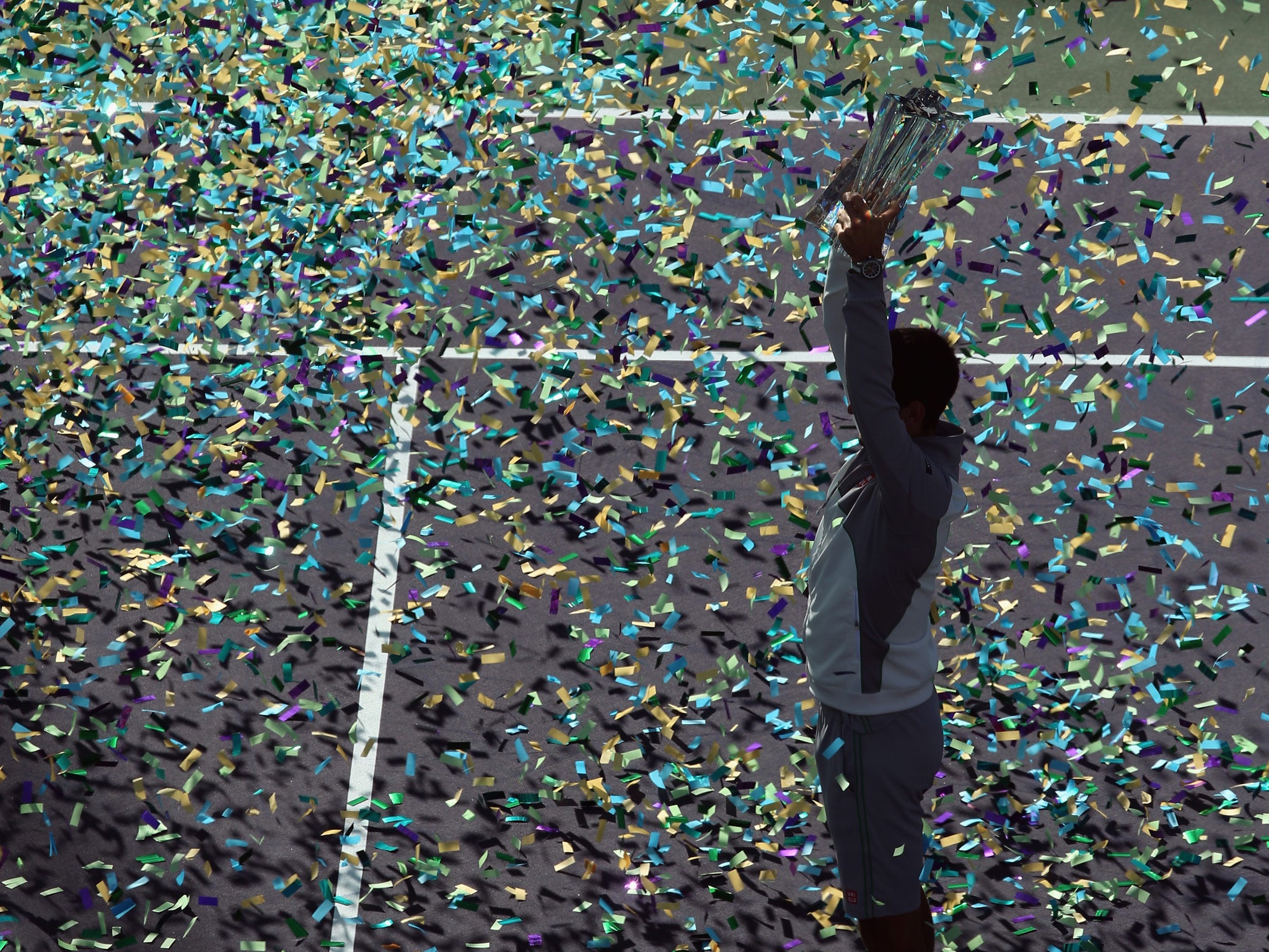 Novak Djokovic of Serbia celebrates with the trophy following his victory over Roger Federer in the final of the BNP Paribas Open at Indian Wells