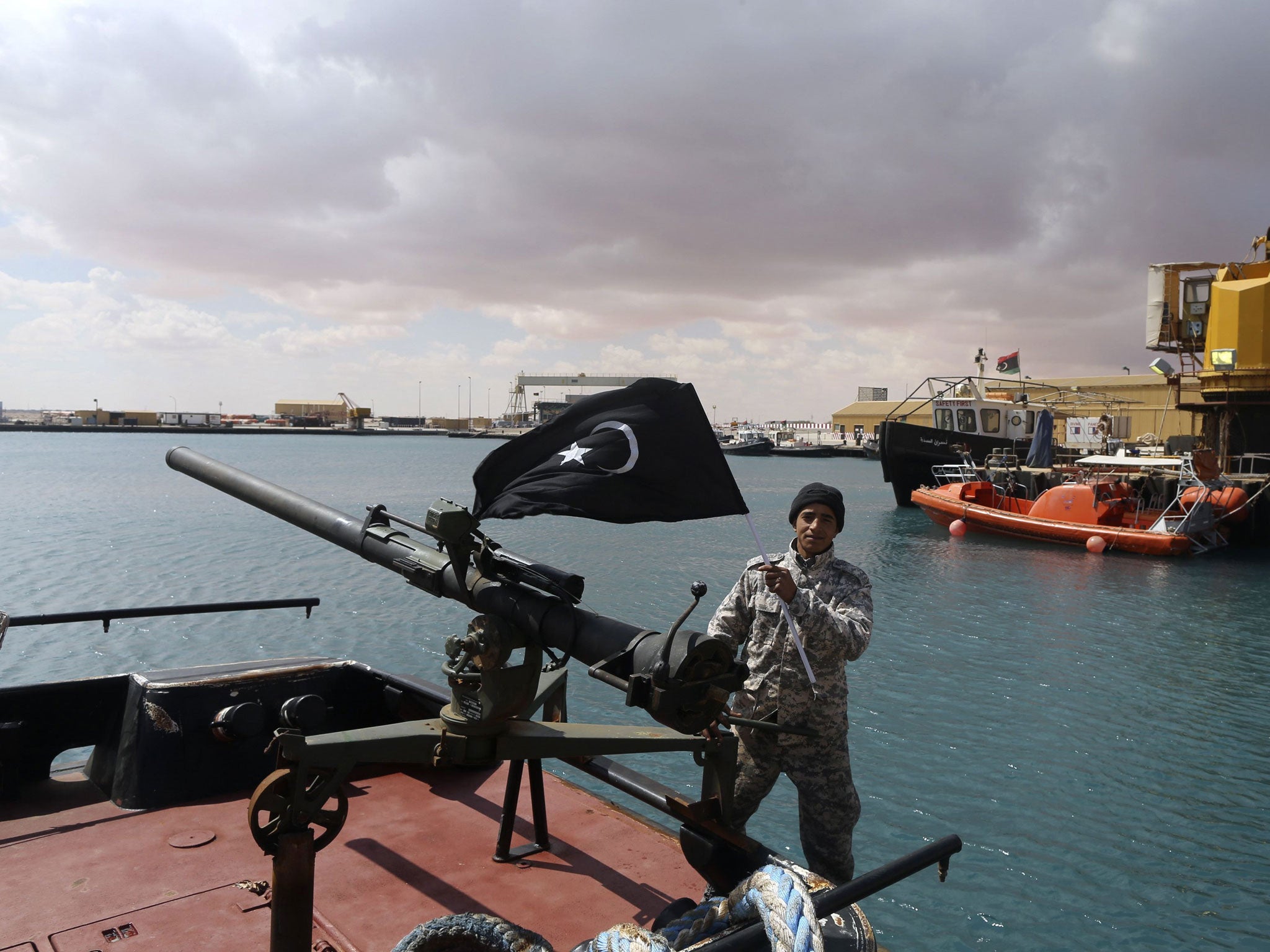 A rebel in the As-Sidra port holds the flag of the eastern Libyan region of Cyrenaica, 11 March 2014 (Reuters)