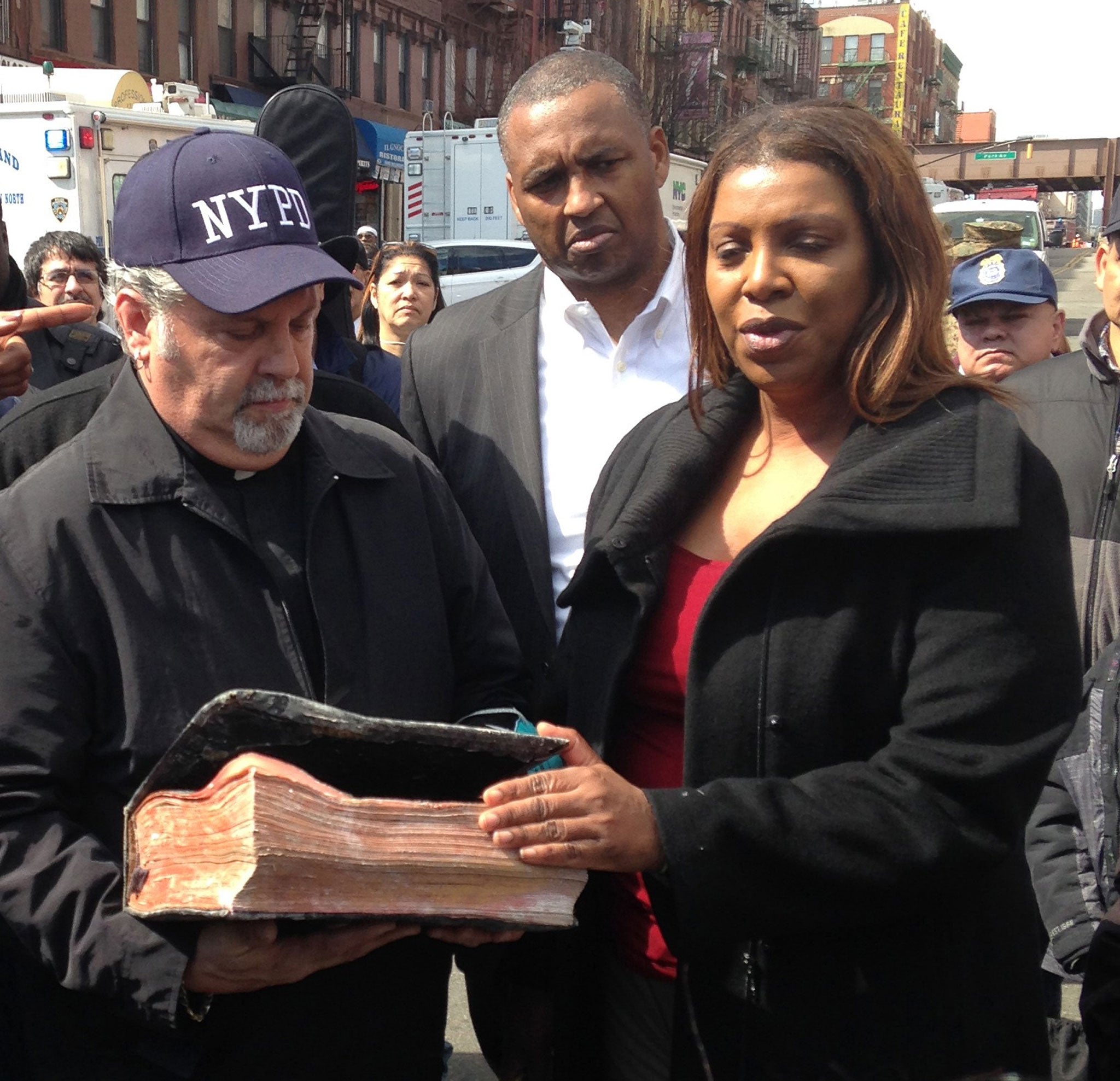 Pastor Rick Del Rio and New York City public advocate Letitia James display a damaged but intact Bible they said was recovered in the rubble of the Spanish Christian Church