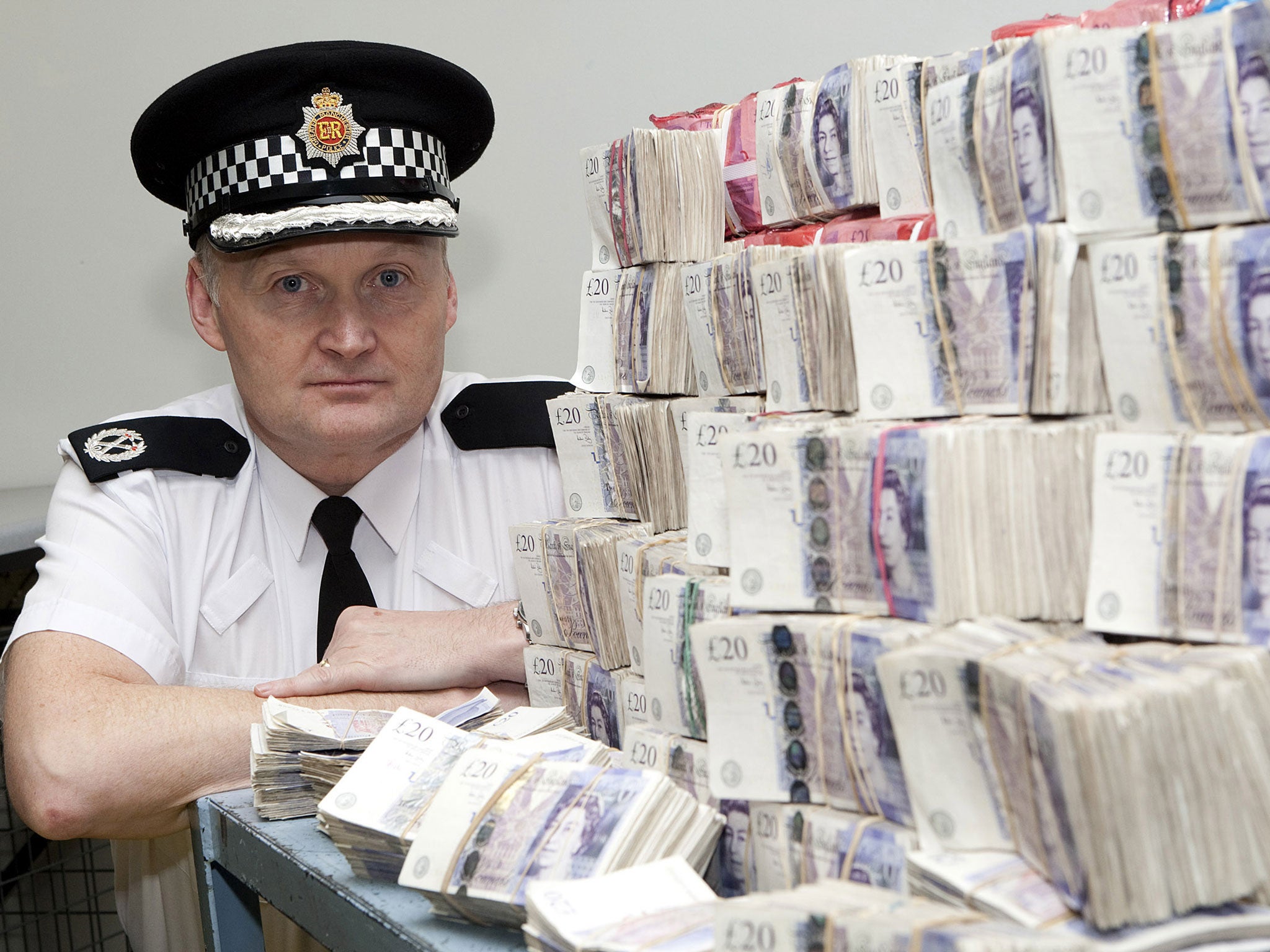 Assistant Chief Constable Terry Sweeney, pictured here with cash seized from police raids, has stepped down from his role following the launch of a corruption inquiry