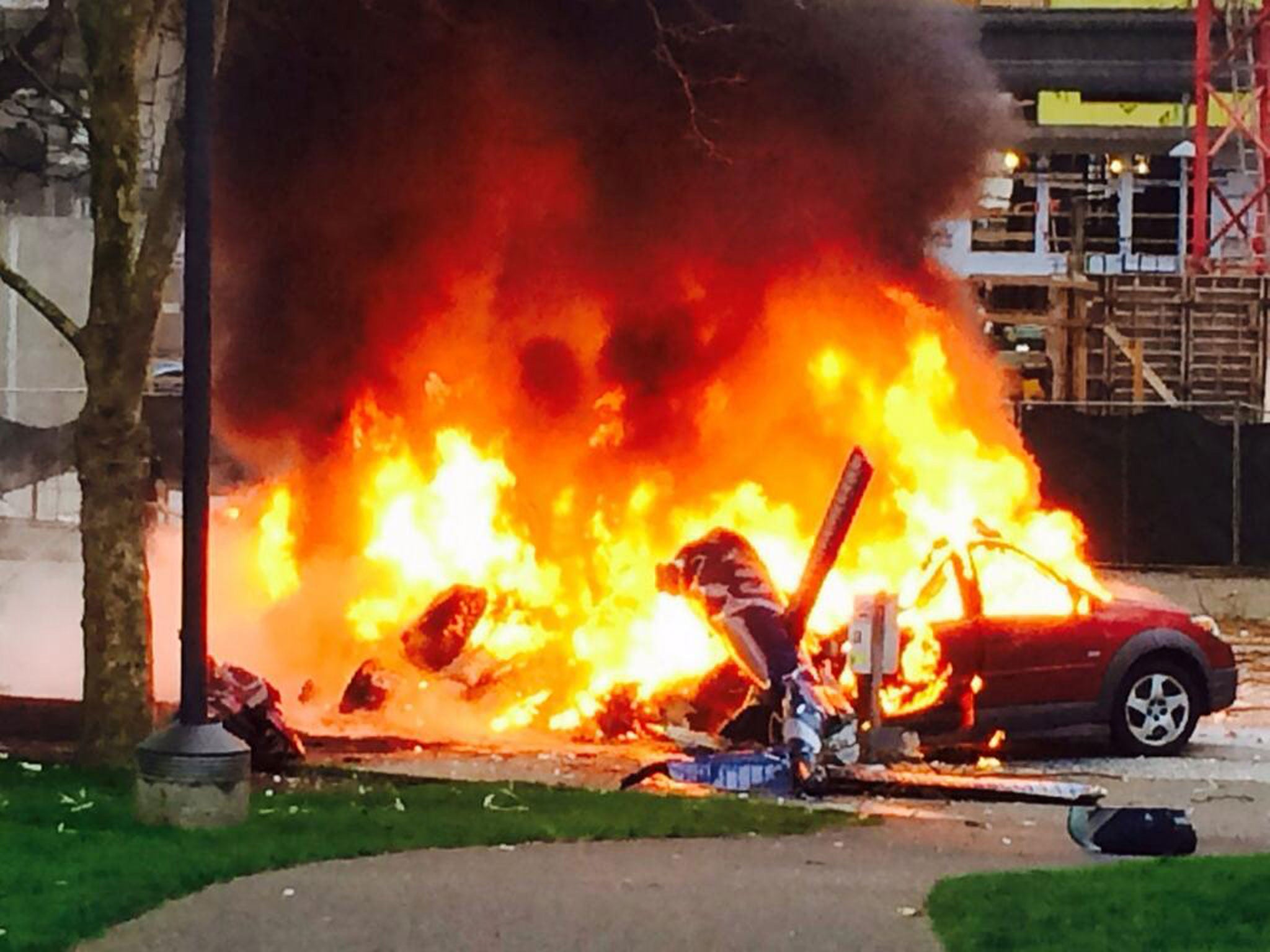 A car burns at the scene of a helicopter crash outside the KOMO-TV studios near the space needle in Seattle