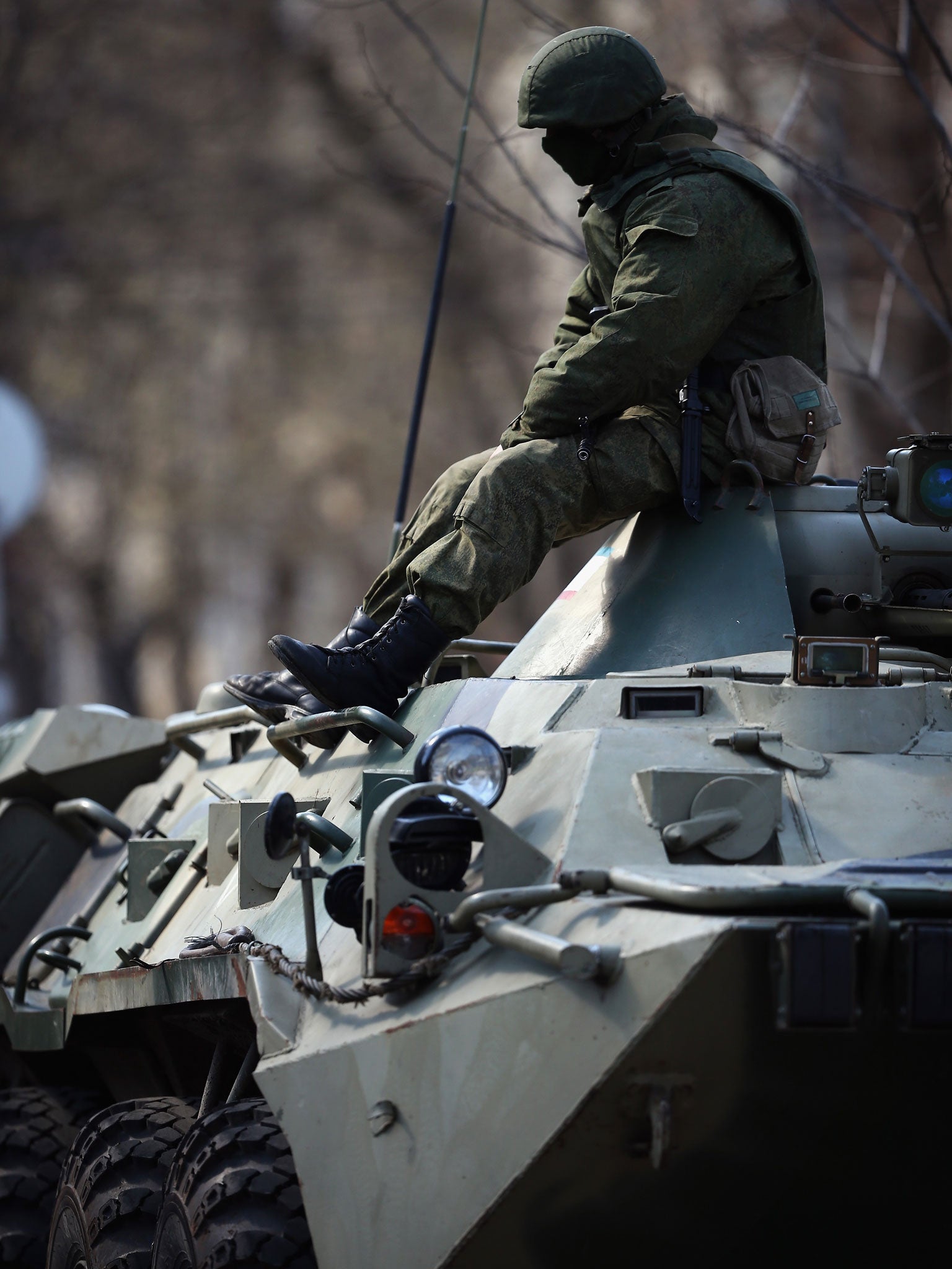 A Russian military man sits on top of a Russian military personnel carrier outside a Ukrainian military base on March 18, 2014 in Simferopol, Ukraine