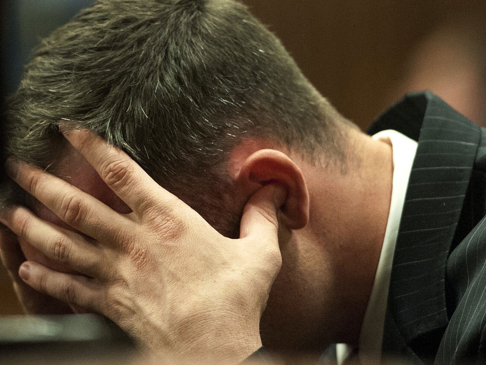 Oscar Pistorius holds his head in his hands in the dock during cross examination of a witnesses in court in Pretoria