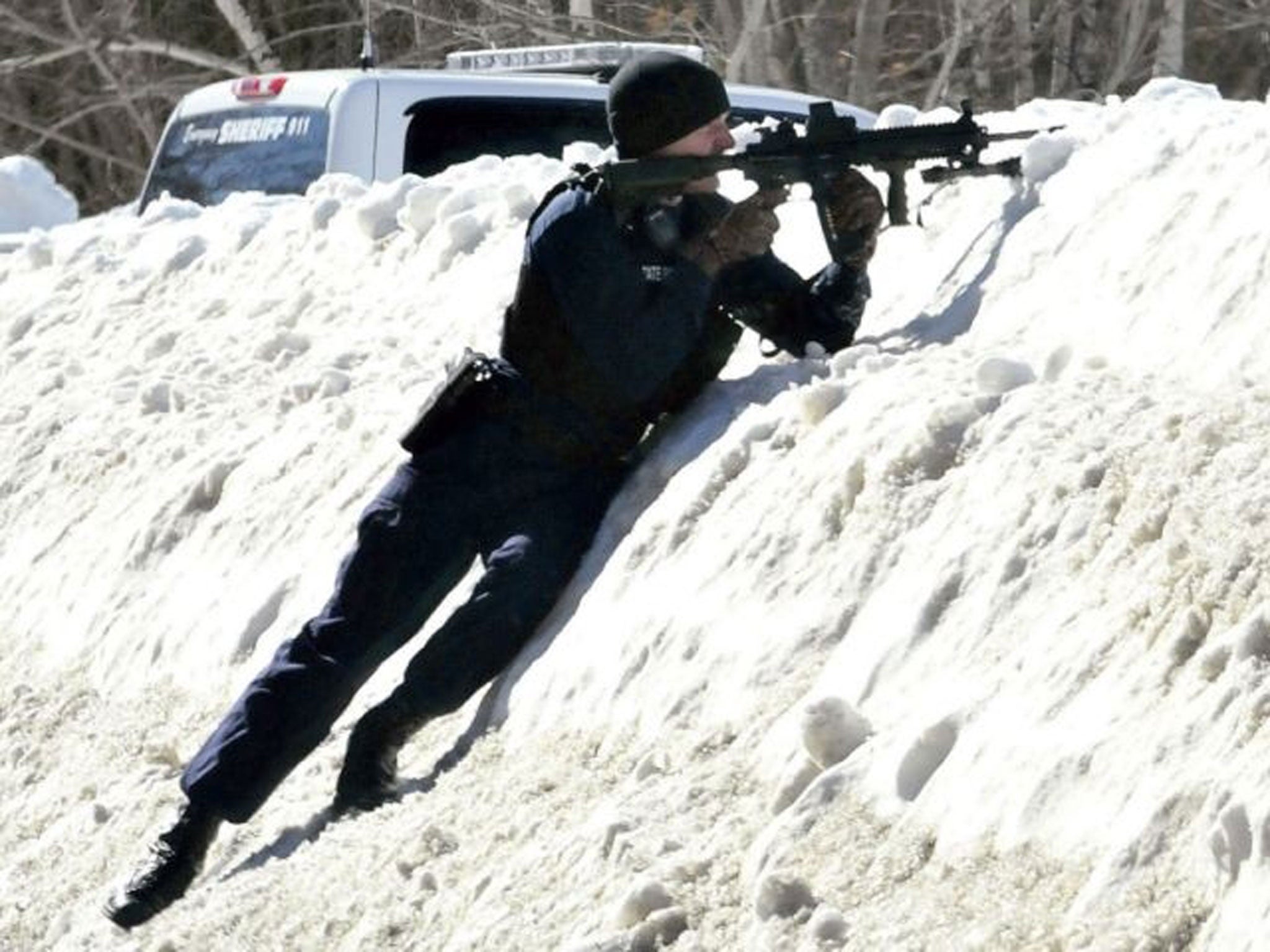 A trooper points his rifle toward the home of Michael Smith in Norridgewock, Maine.