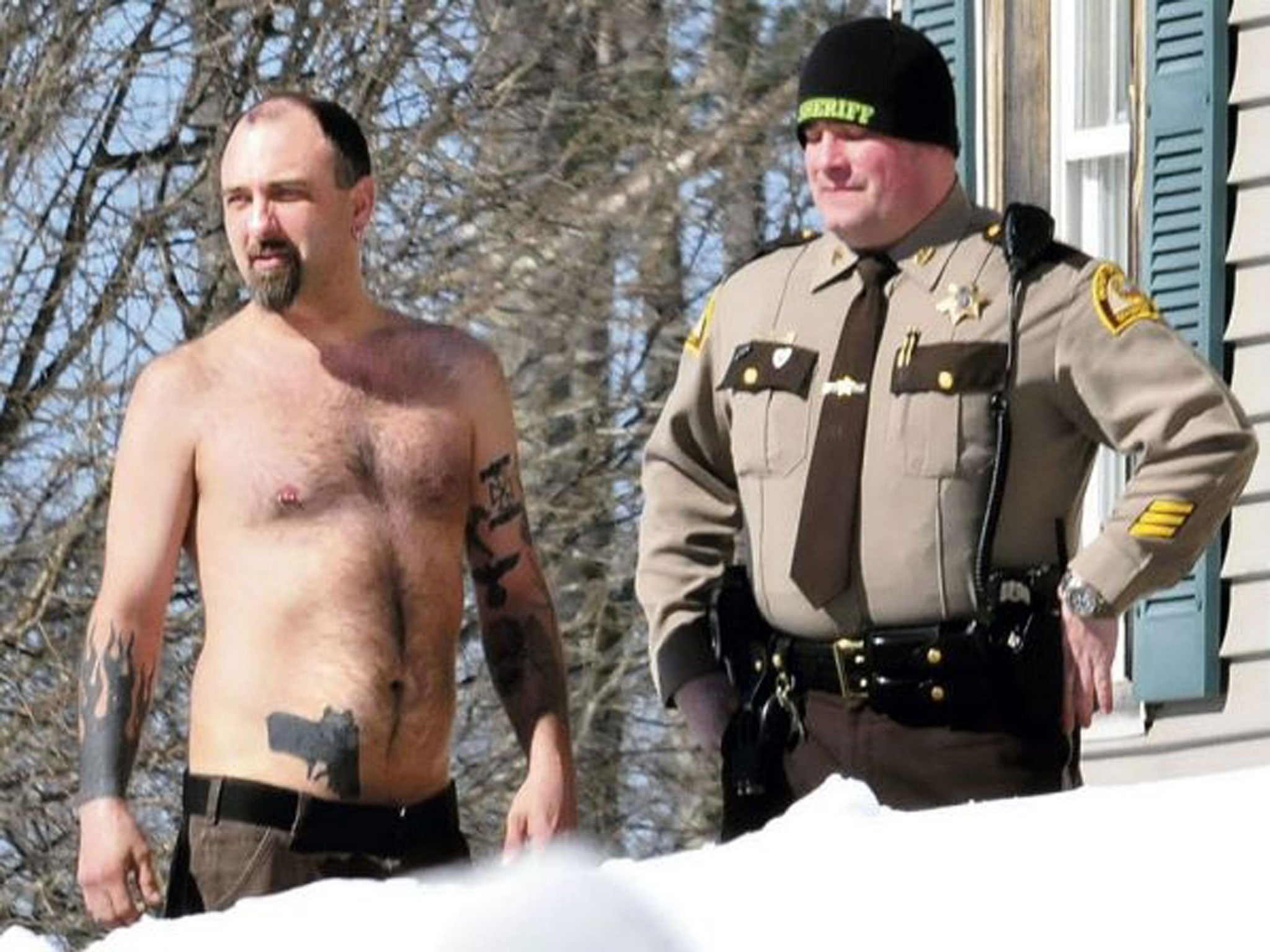 Michael Smith, left, stands beside a Somerset County Sheriff deputy outside his home in Norridgewock, Maine. Officers armed with assault rifles descended on Smith's home after members of a tree removal crew he'd told to clear off his property reported tha