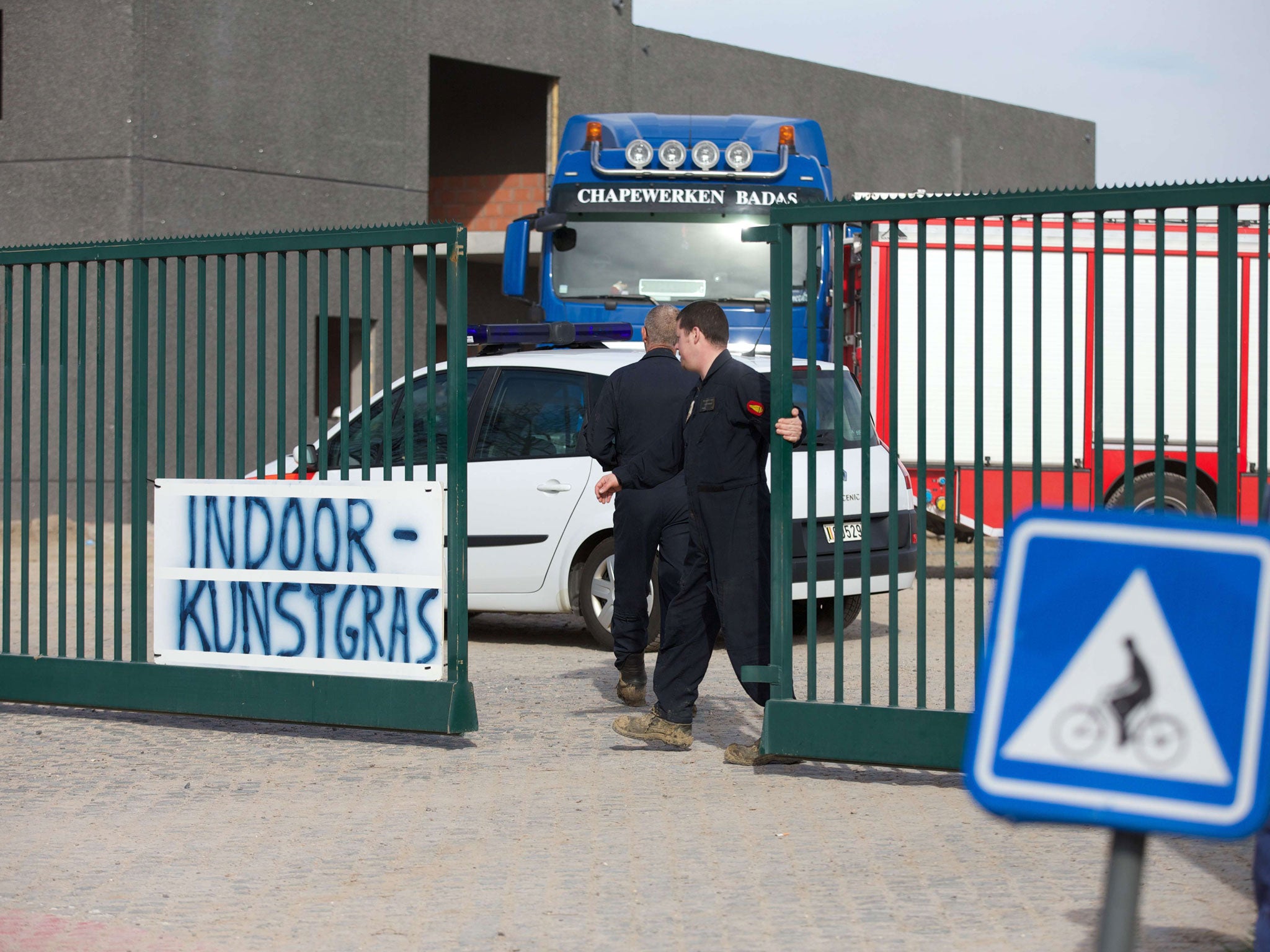A man closes the gate to an industrial site where a World War I era shell exploded during excavation works on March 19, 2014, in Ypres, Belgium, killing two workers and severely injuring another.